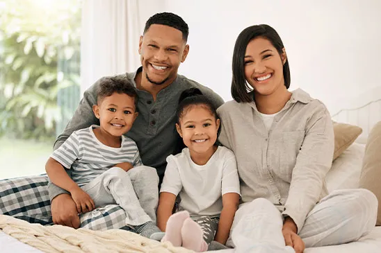 Uma familia feliz com dois filhos pequenos na cama em conforto.